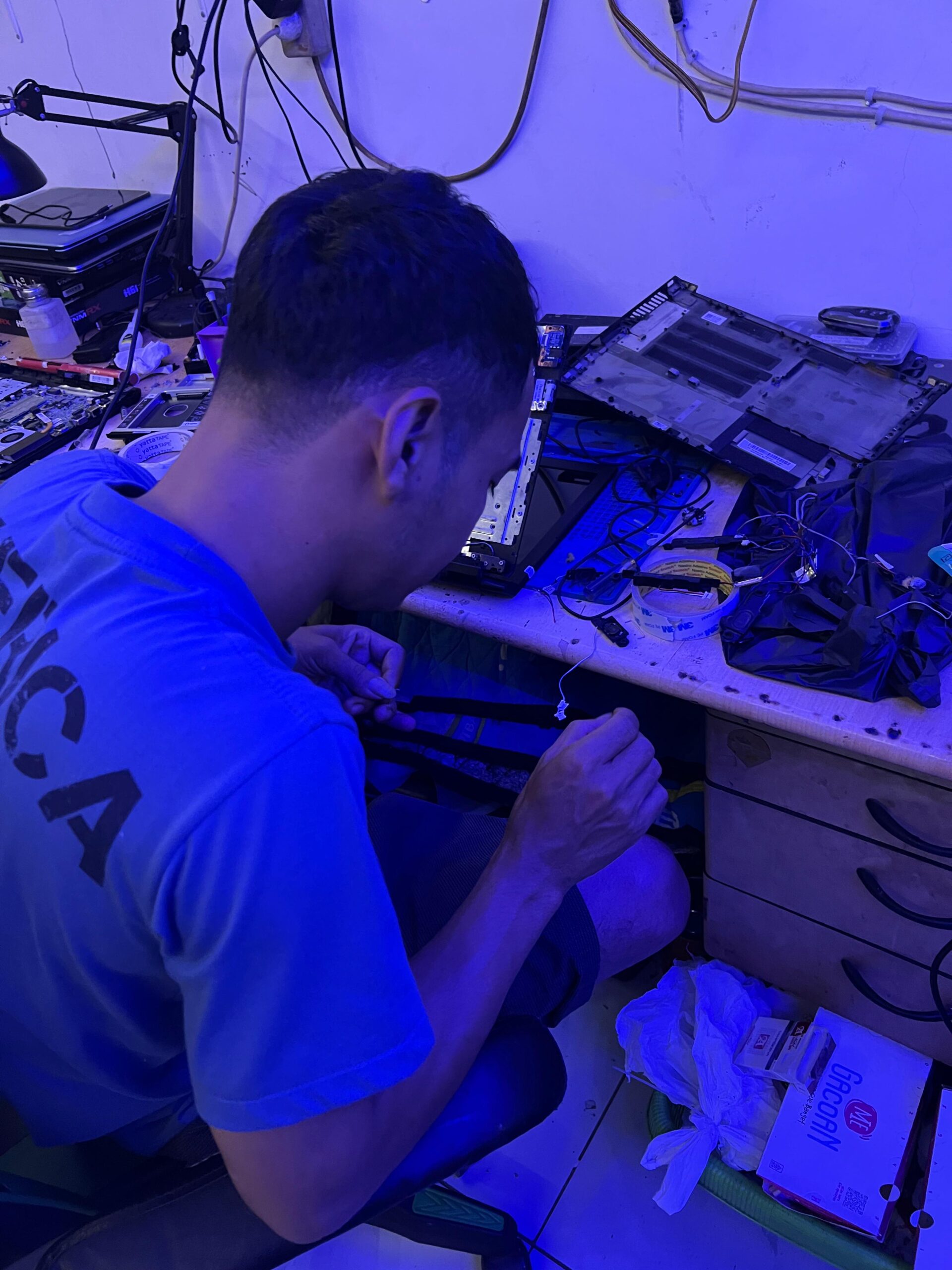 Teknisi laptop di Hanz Com Laptop Beji Depok sedang melakukan pemeriksaan kerusakan pada motherboard.