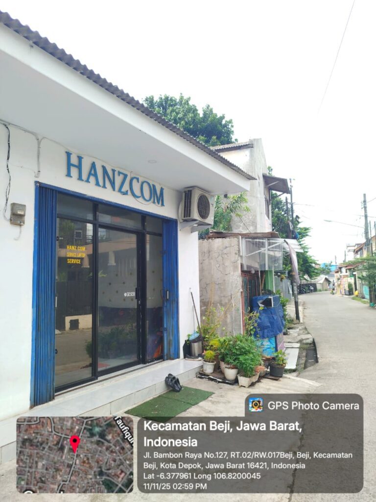 Tampak samping Toko HanzCom Laptop dari sudut samping dengan pot tanaman di depan. Lokasi berada di Jl. Bambon Raya, Beji, Depok, dekat dengan pemukiman dan akses jalan lingkungan.
