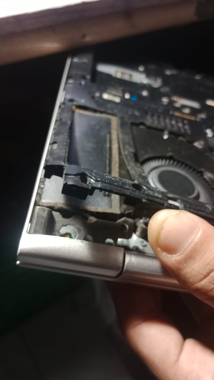 Foto kerusakan engsel laptop pada bagian sudut bawah, menunjukkan dudukan bracket yang patah dan casing yang terangkat akibat torsi engsel terlalu berat. Terlihat struktur dalam laptop dan kipas pendingin, menggambarkan kasus kerusakan engsel yang sering ditemukan pada pengguna laptop di Depok