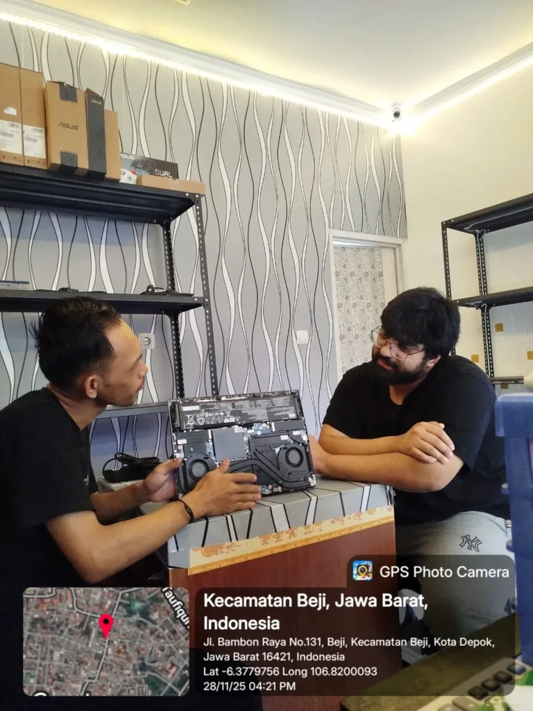 Teknisi sedang berdiskusi dengan Customer sambil memeriksa bagian dalam sebuah laptop yang terbuka di atas meja service dan menjelaskan kondisi komponen Laptop akibat terkenan air lokasi Kecamatan Beji, Kota Depok